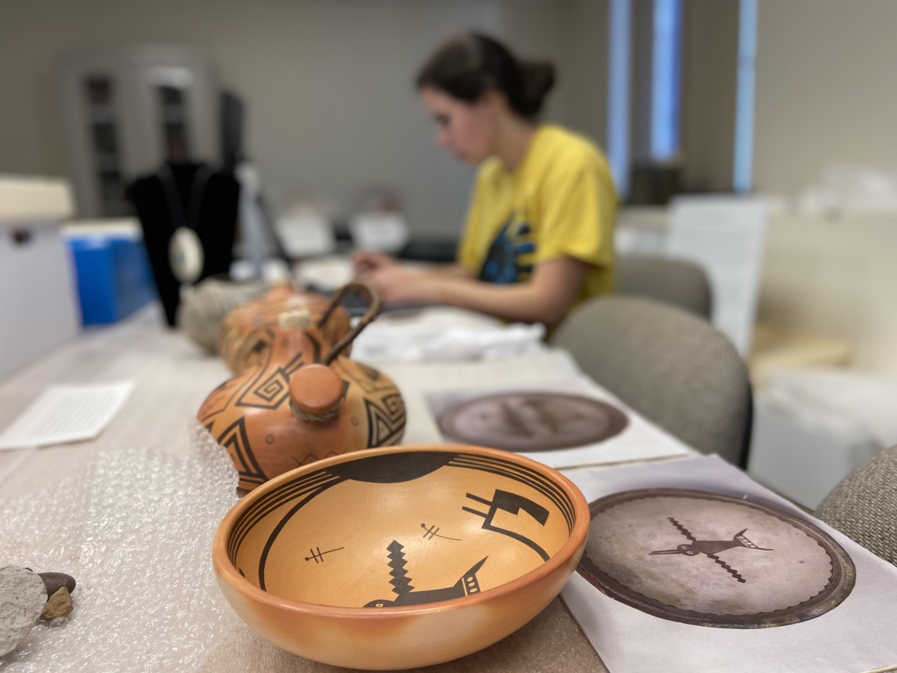 Student working at desk inventorying ceramics