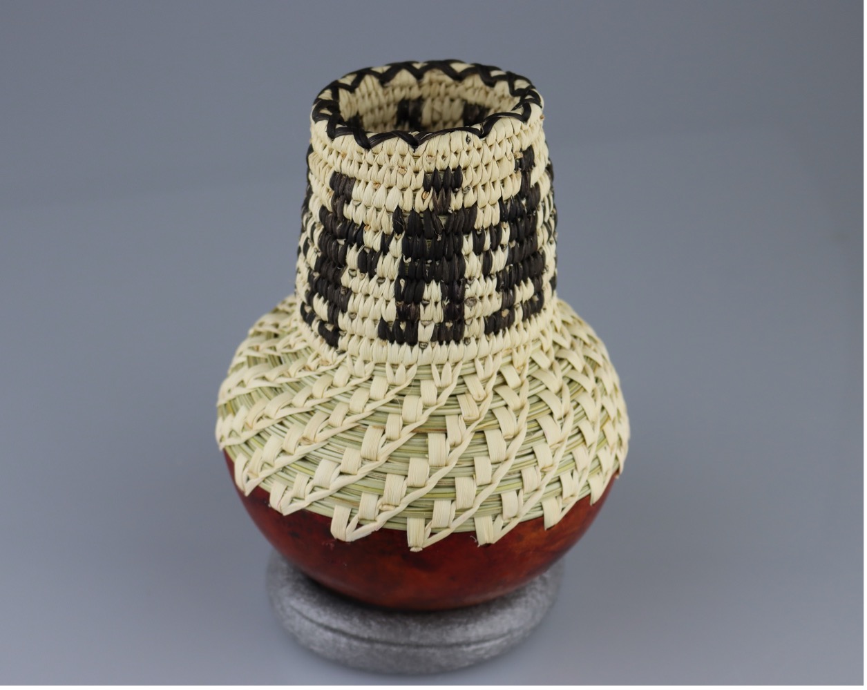 woven vessel with brown gourd shell bottom and woven top with black figures